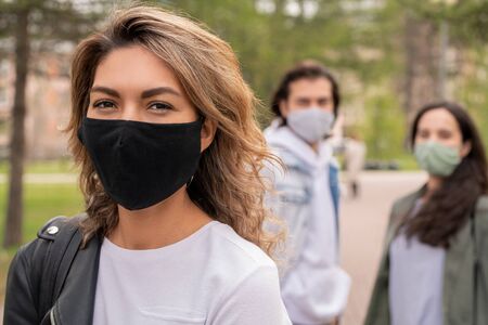 Young woman in white t-shirt, leather jacket and protective black textile maskの写真素材