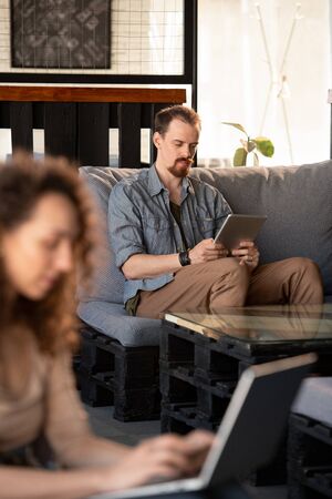 Young serious businessman with touchpad scrolling through online data