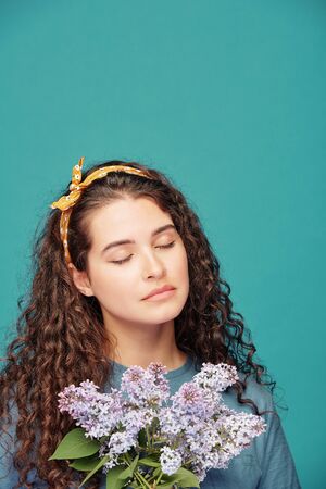 Pretty young serene female with darl long hair keeping her eyes closedの写真素材