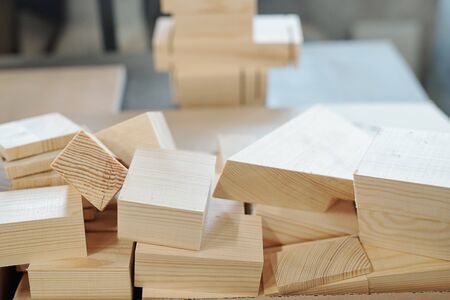 Pile of wooden bricks lying on workbench in large workshop of furniture factoryの写真素材