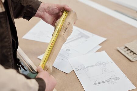 Modern factory worker measuring wooden part of furniture over sketchesの写真素材