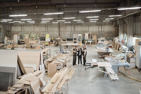 Group of contemporary factory workers discussing furniture producing materialsの写真素材