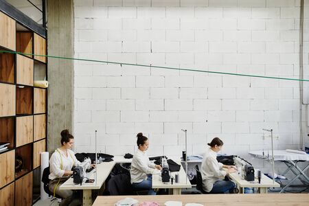 Three young contemporary female designers of fashion sewing new clothes