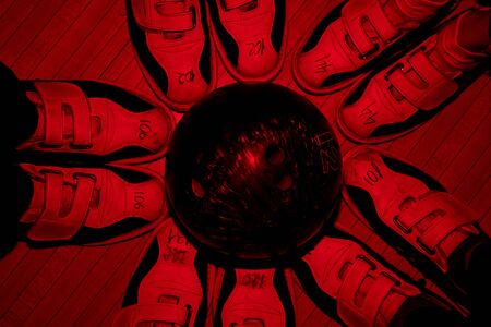 Black bowling ball in the middle of circle made up of footwear of five friendsの写真素材