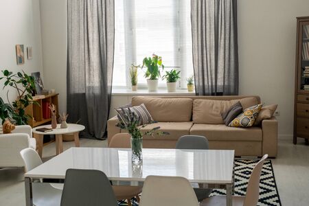 Interior of comfortable domestic room in a flat or house with table in the center surrounded by...