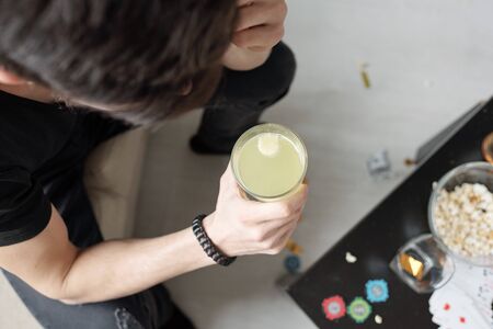 Above view of man drinking hangover cure in morning after home partyの写真素材