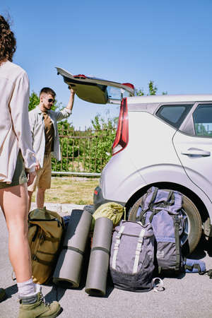 Young man looking at trunk while going to load all the bags and backpacksの写真素材