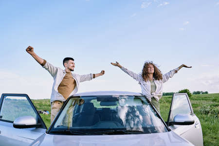 Happy young man and woman with outstretched arms enjoying warm summer dayの写真素材