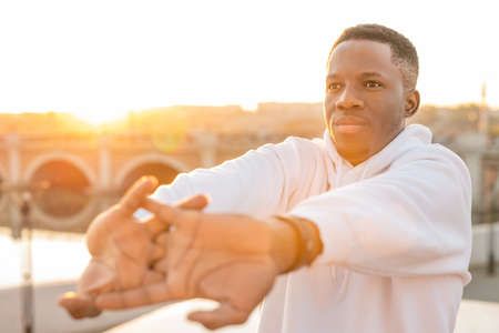 Young African sportsman exercising with his arms stretched in front of himselfの写真素材