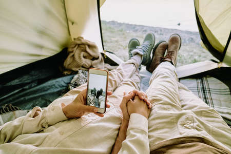 Young amorous female holding her husband by hand and taking photo of themの写真素材