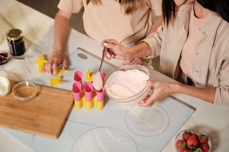 Hands of young female putting mixture of homemade icecream ingredients