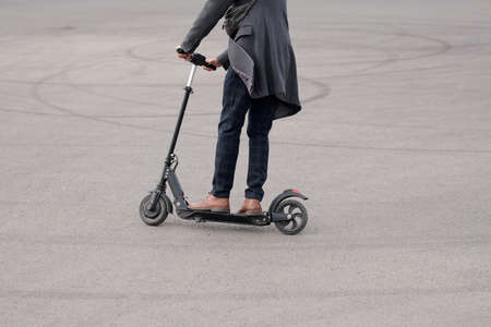 Low section of young contemporary businessman moving down asphalt road to work