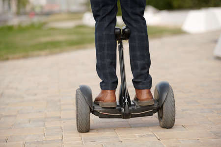 Legs of young contemporary man in pants and boots standing on gyroscope