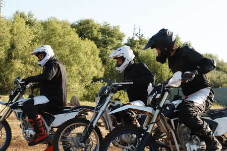 Group of male motorcyclists in helmets being at starting line while preparing for race