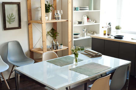 White rectangular table with bunch of wildflowers in vase between grey napkins