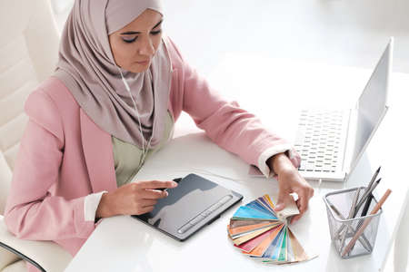 Above view of concentrated young Arabian graphic designer choosing color for design in officeの写真素材