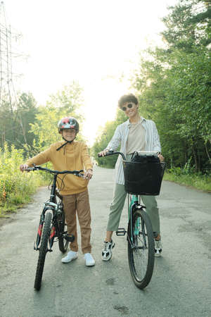 Happy young mother in casualwear and sunglasses and her youthful son in helmet