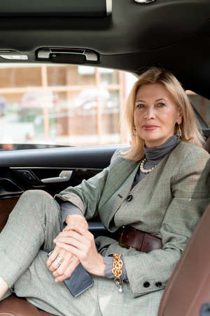 Businesswoman sitting on backseat of taxi cab on her way to appointment