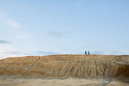 Tiny silhouettes of researchers in protective coveralls moving on top of hillの写真素材