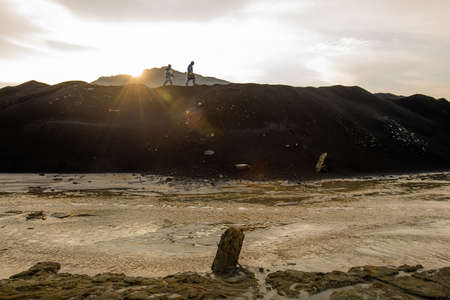 Tiny silhouettes of two contemporary researchers moving along hilltop