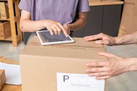 Hand of young female manager of online shop pointing at screen of digital tabletの写真素材