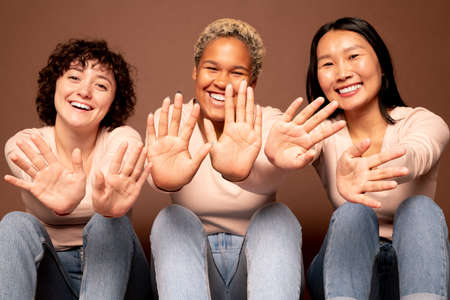 Joyful young smiling women of various ethnicities showing their palms to youの写真素材