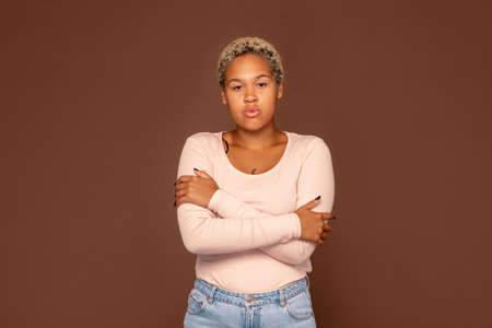 Pretty young mixed-race female in jeans and pullover crossing arms on chestの写真素材