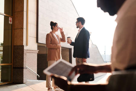 Focus on business colleagues standing at office entrance and discussing new project in background