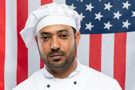 Young confident mixed-race chef of restaurant in white uniform looking at you