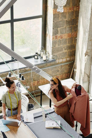Happy young creative woman showing her colleague new models on laptop display