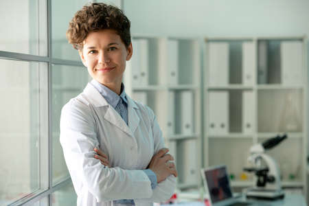 Happy young successful researcher in whitecoat standing in front of camera