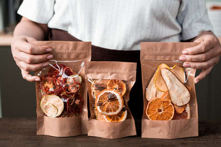 Close-up of unrecognizable woman presenting packages of sweet dried fruit mixture, healthy foodの写真素材