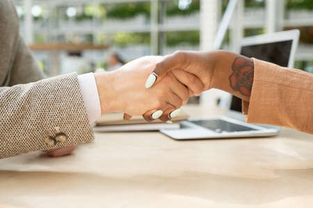 Handshake of young intercultural business partners over table after making dealの写真素材