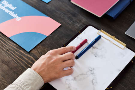 Hand of young contemporary manager taking crimson highlighter off blank paperの写真素材