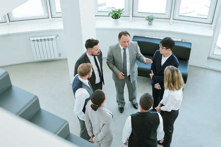 Several intercultural business partners standing inside office at meeting