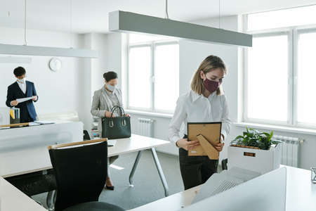 Group of contemporary business people taking out office supplies out of boxes