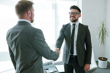 Mature successful businessman in formalwear looking at his business partner