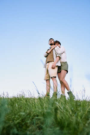 Below view of serene girl hugging young boyfriend while they enjoying beauty of country scape togetherの写真素材
