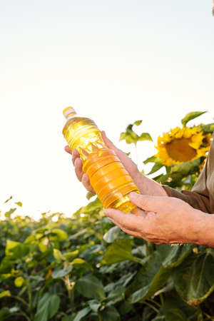 Hands of contemporary senior farmer holding bottle of sunflower oilの写真素材