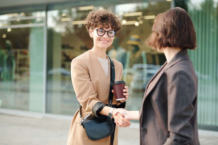Two young female colleagues or business partners shaking hands after negotiatingの写真素材