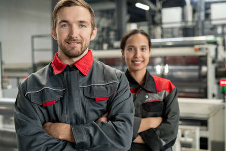 Happy young bearded male leader of workteam standing against female colleagueの写真素材