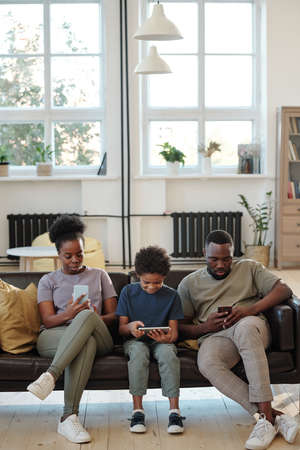 Contemporary young family of father, mother and cute little son using gadgetsの写真素材