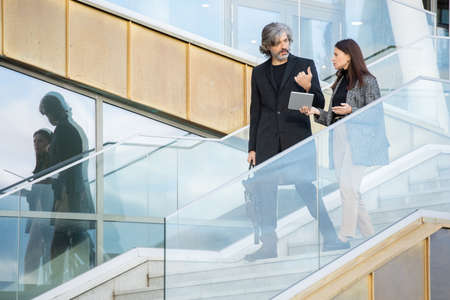 Mature businessman and his young colleague discussing working points on the moveの写真素材