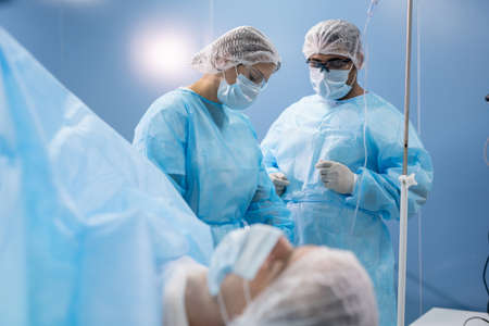 Young female assistant in protective workwear preparing medical instruments