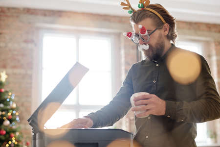 Young bearded businessman in xmas eyeglasses with white moustache making copy