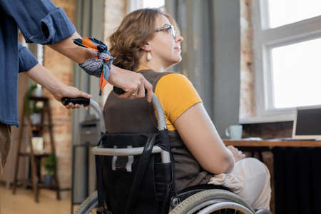Hands of young woman pushing wheelchair with her disable sister or friendの写真素材