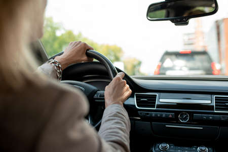 Hands of contemporary mature businesswoman holding by steer while driving