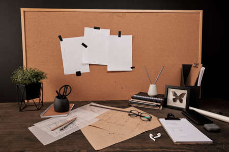 Workplace of engineer with carton board by table with various office supplies