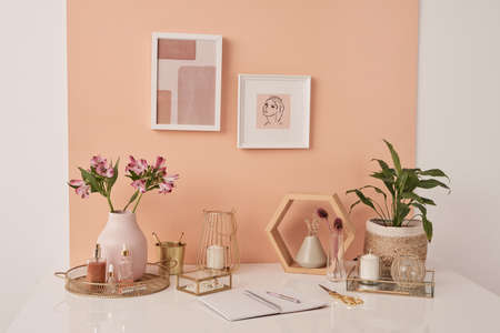 Workplace of interior designer with flowers, beauty products, candles on table