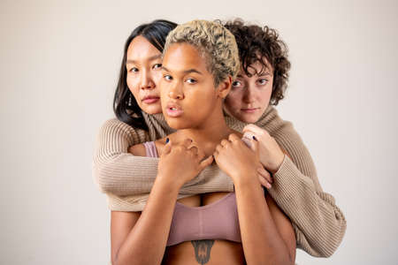 Women of Caucasian and Asian ethnicities in one sweater embracing African girlの写真素材